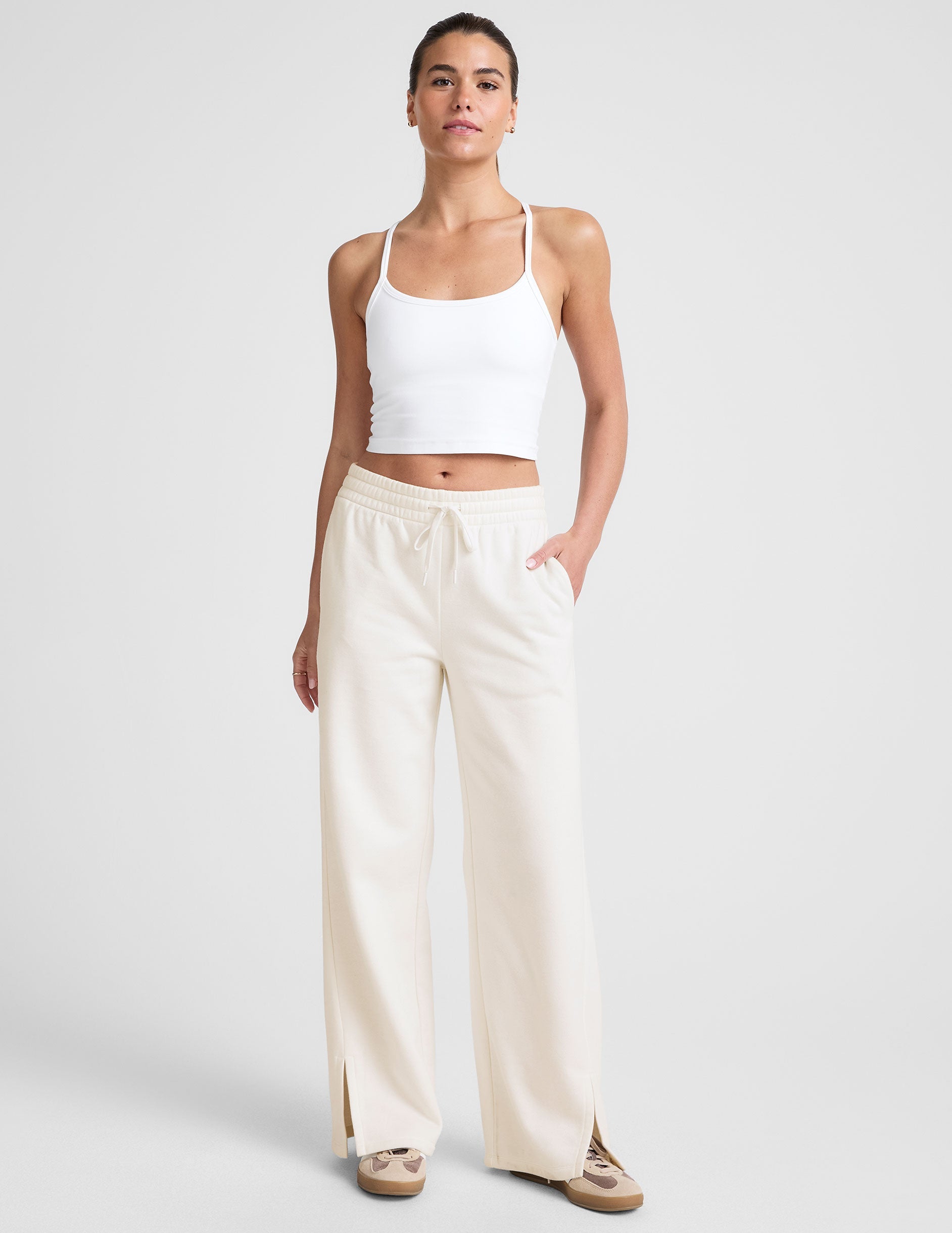 white mid-rise wide leg sweatpants with side slits and a drawcord at waistband.