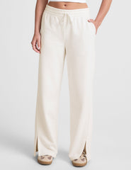 white mid-rise wide leg sweatpants with side slits and a drawcord at waistband.