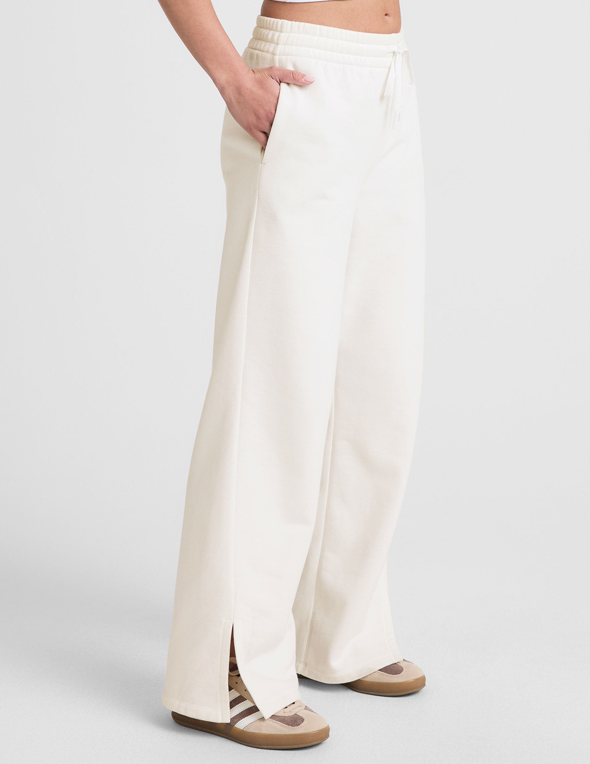 white mid-rise wide leg sweatpants with side slits and a drawcord at waistband.