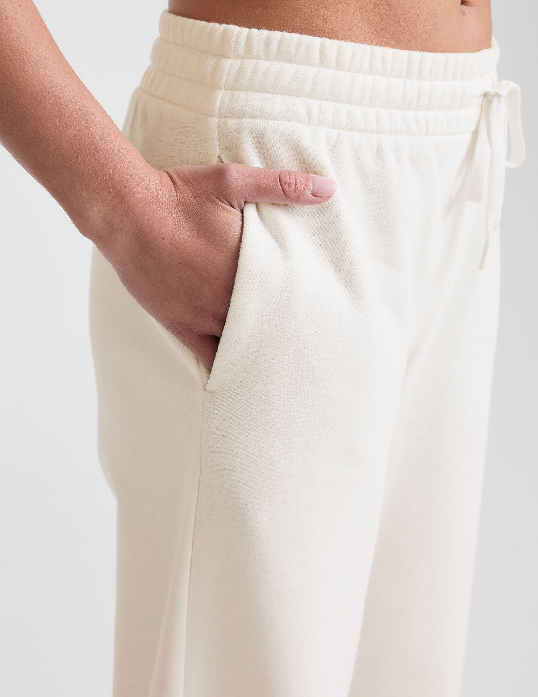 white mid-rise wide leg sweatpants with side slits and a drawcord at waistband.