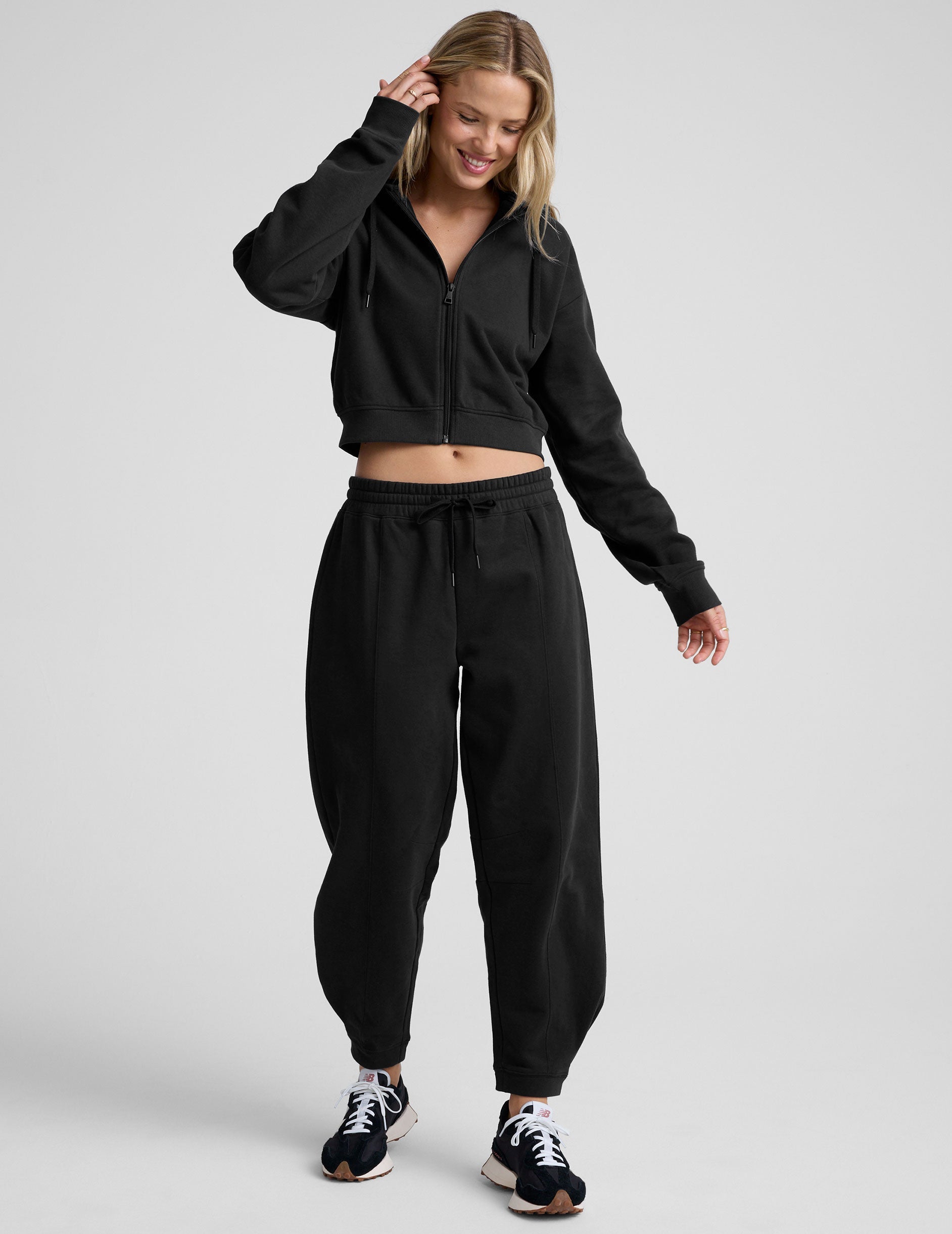 model is wearing black fleece barrel style sweatpants against a plain background.