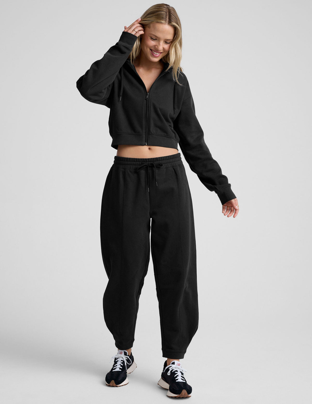 model is wearing black fleece barrel style sweatpants against a plain background.