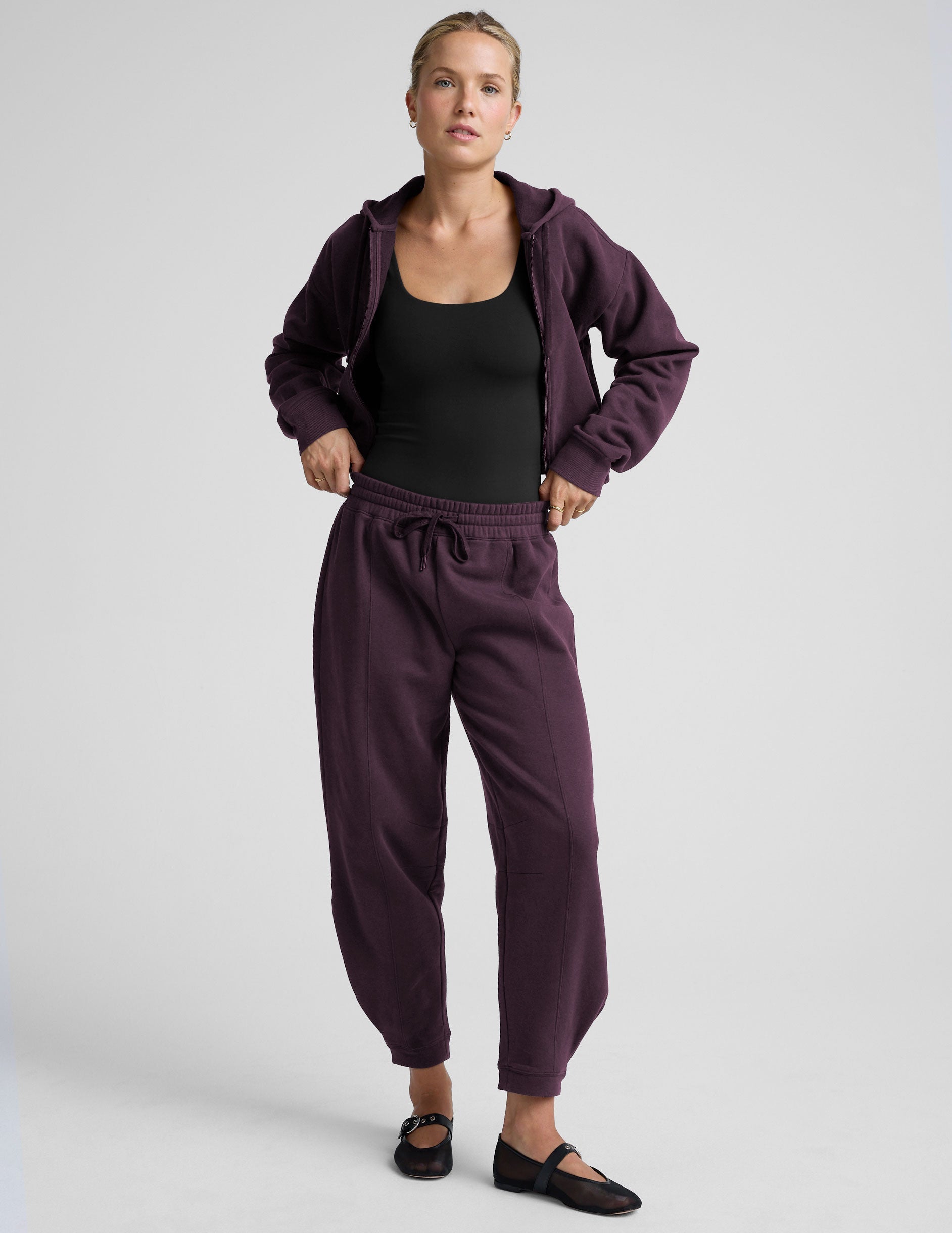 model is wearing purple fleece barrel style fleece sweatpants against a plain background.
