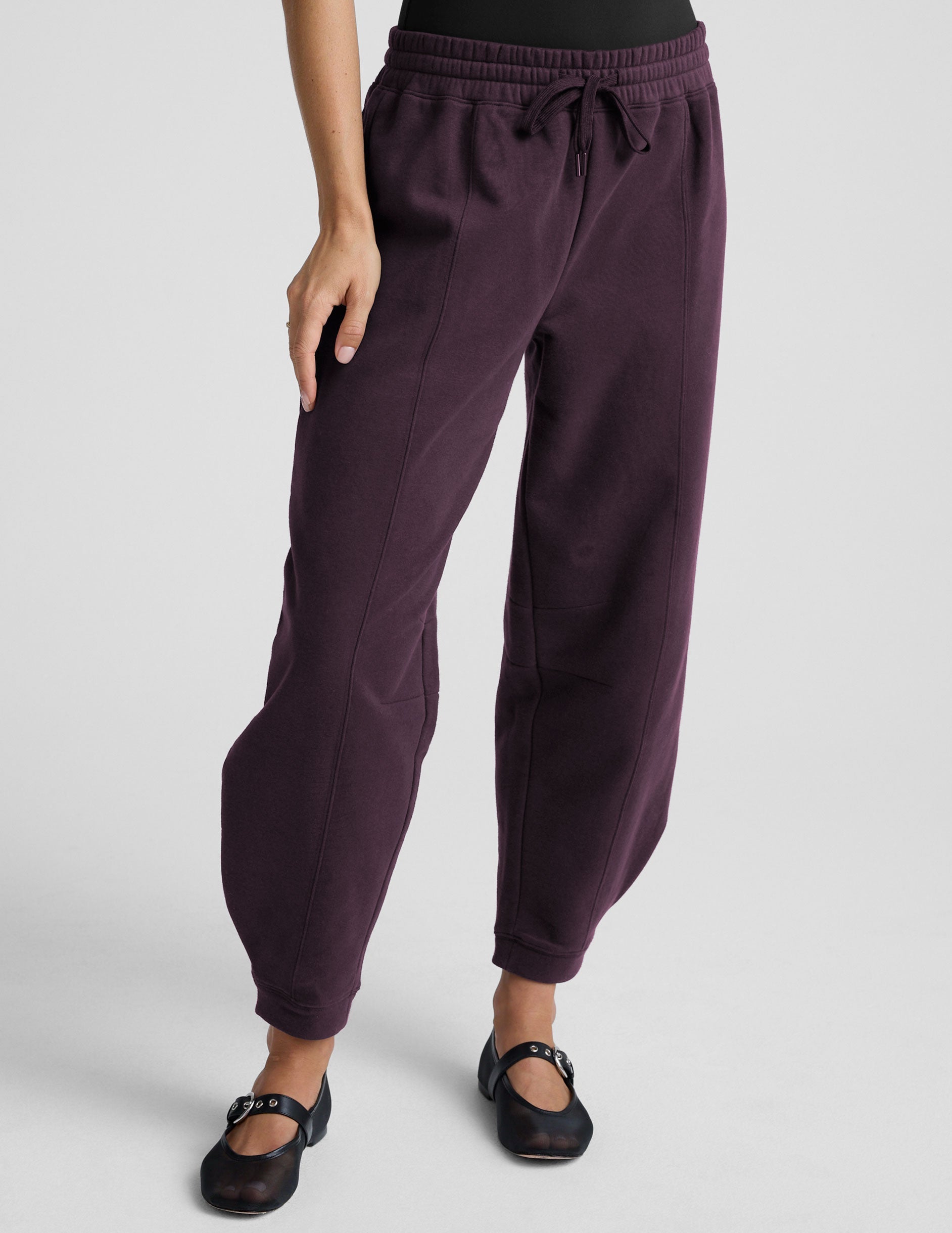 model is wearing purple fleece barrel style fleece sweatpants against a plain background.