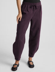 model is wearing purple fleece barrel style fleece sweatpants against a plain background.