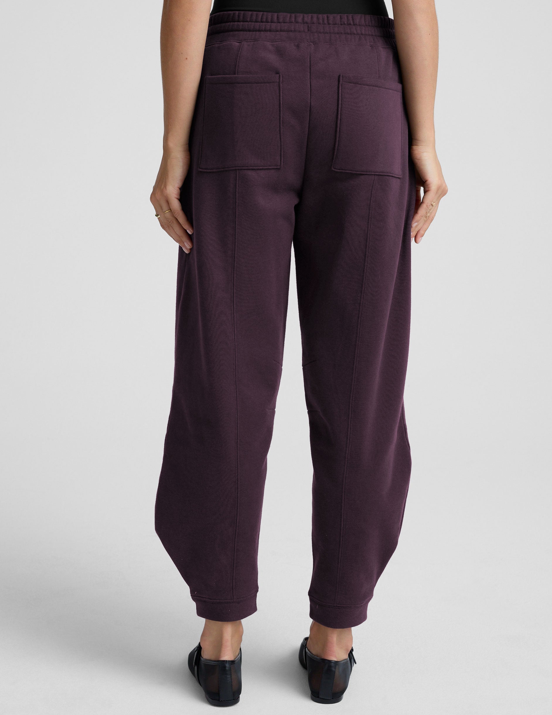 model is wearing purple fleece barrel style fleece sweatpants against a plain background.