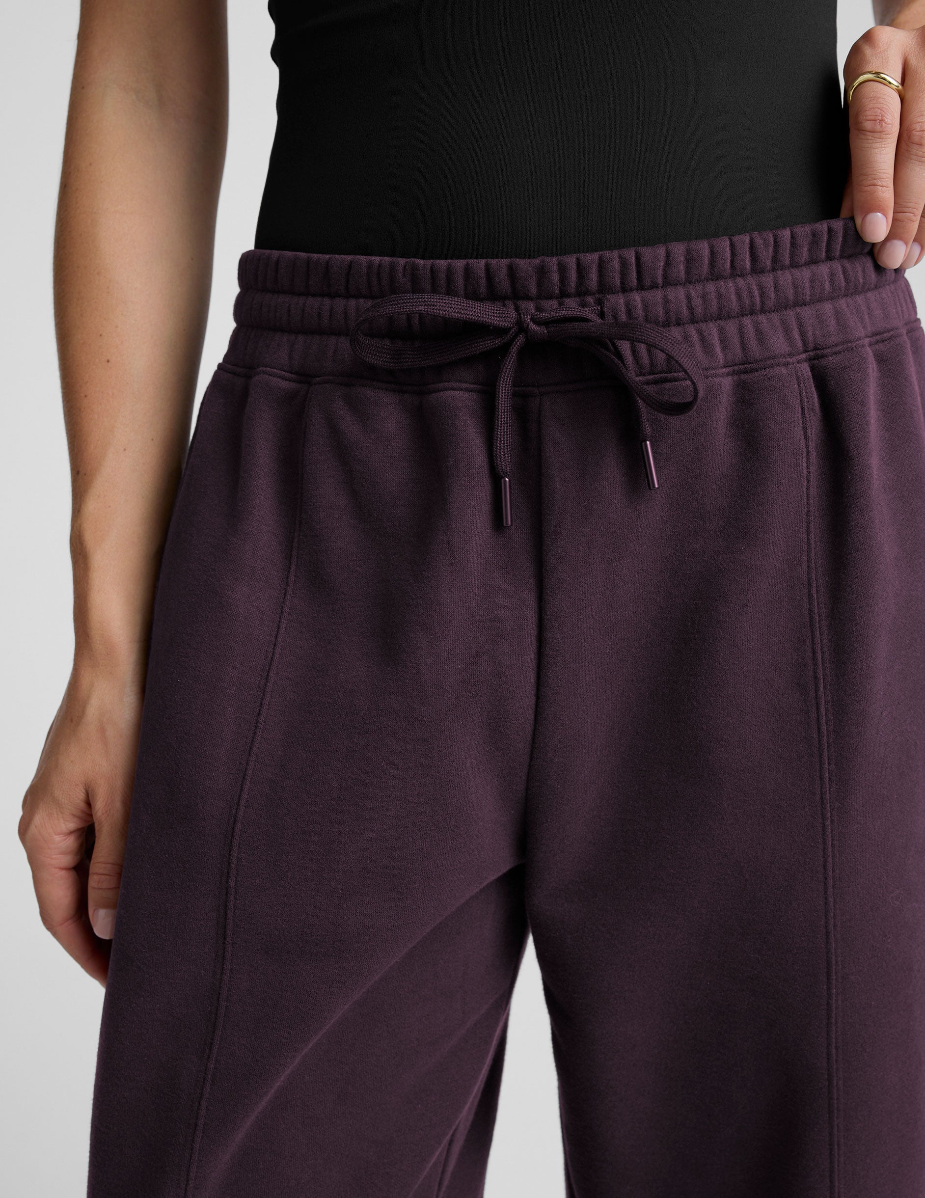 model is wearing purple fleece barrel style fleece sweatpants against a plain background.