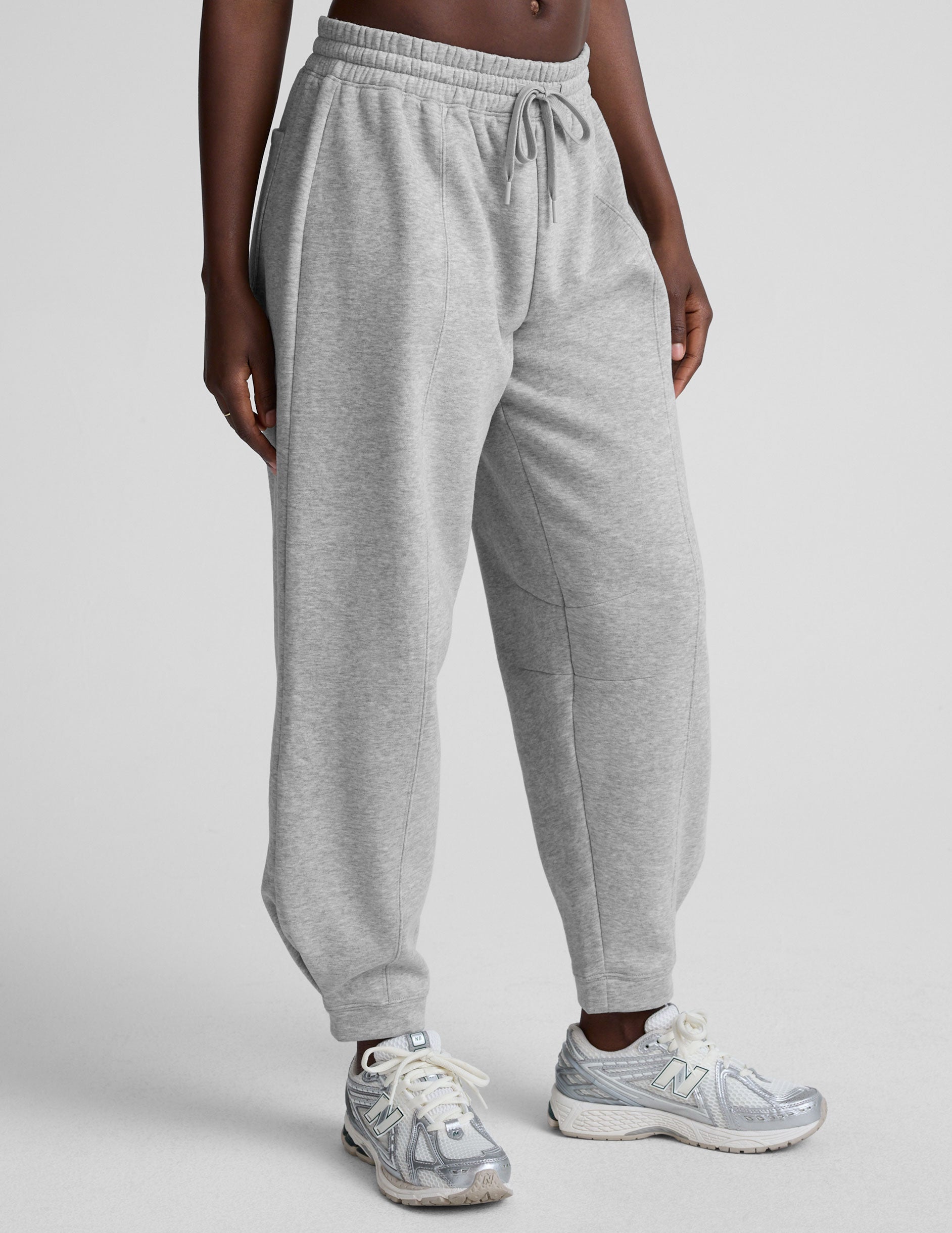model is wearing gray fleece barrel style sweatpants against a plain background.