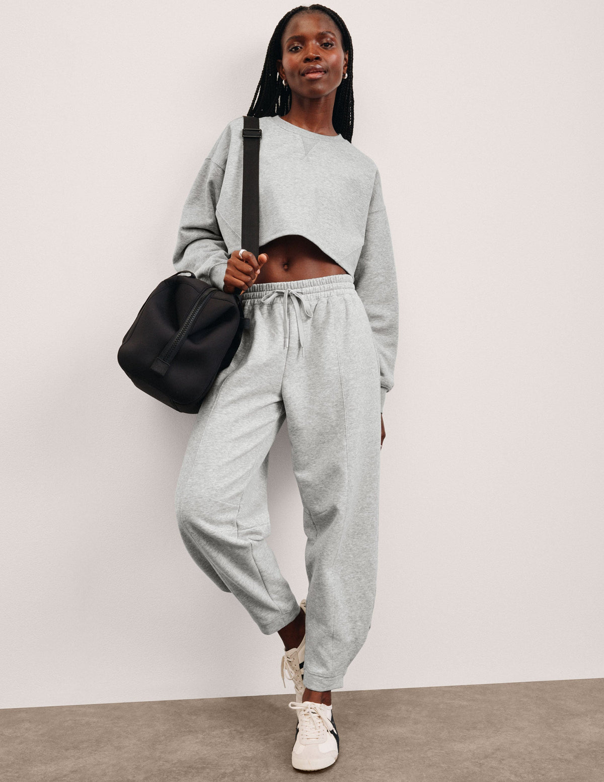 model is wearing gray fleece barrel style sweatpants against a plain background.