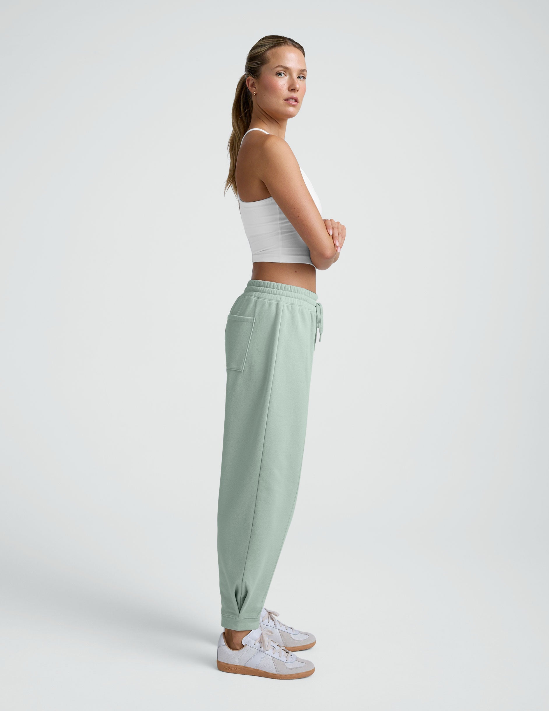 model wearing a white cropped tank and blue barrel style sweatpants against a plain background.