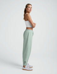 model wearing a white cropped tank and blue barrel style sweatpants against a plain background.