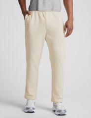 man wearing a cream-colored straight leg fleece sweatpants on a plain background.