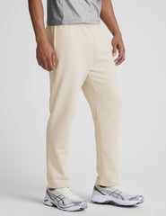 man wearing a cream-colored straight leg fleece sweatpants on a plain background.