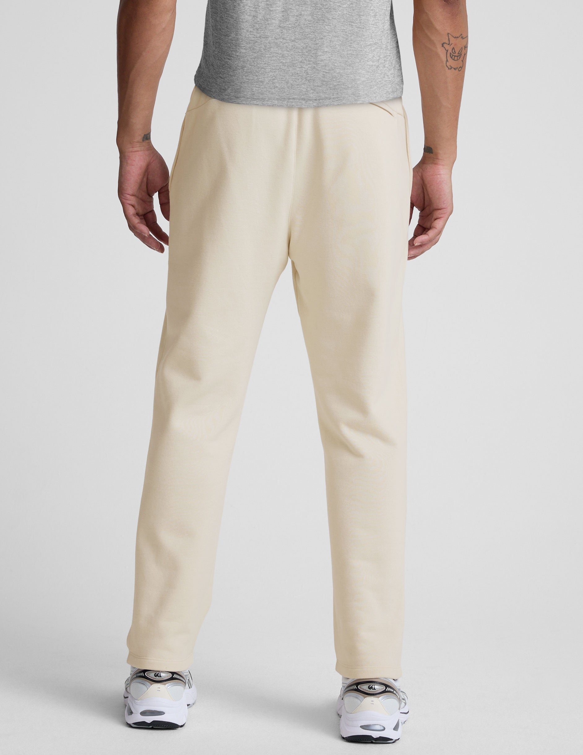 man wearing a cream-colored straight leg fleece sweatpants on a plain background.
