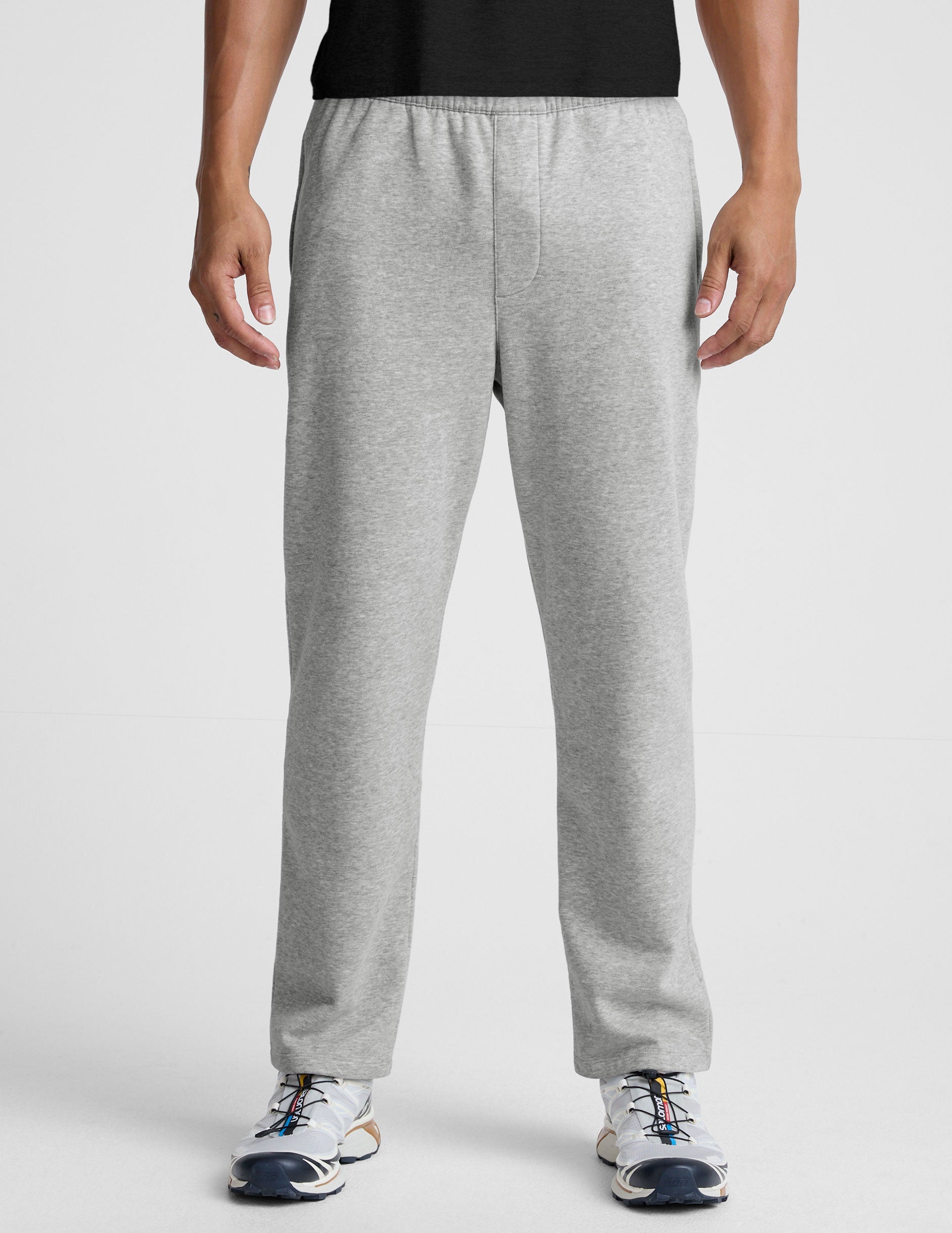 man wearing a gray straight leg fleece sweatpants on a plain background.