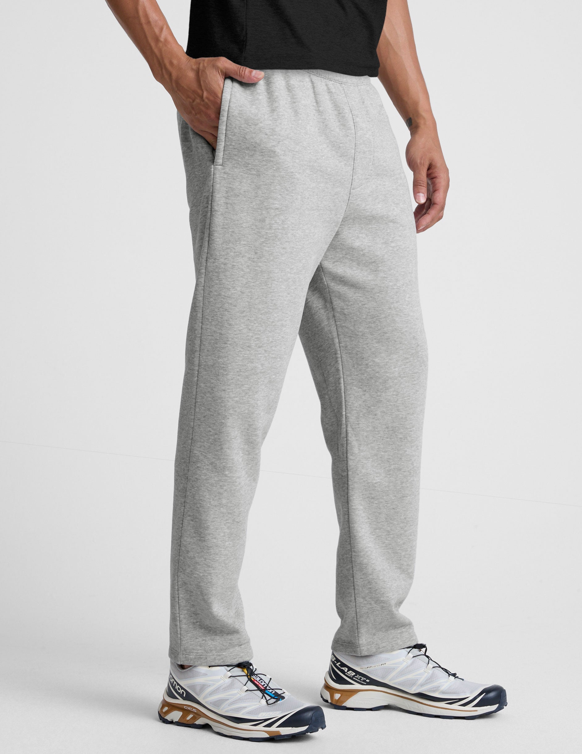 man wearing a gray straight leg fleece sweatpants on a plain background.