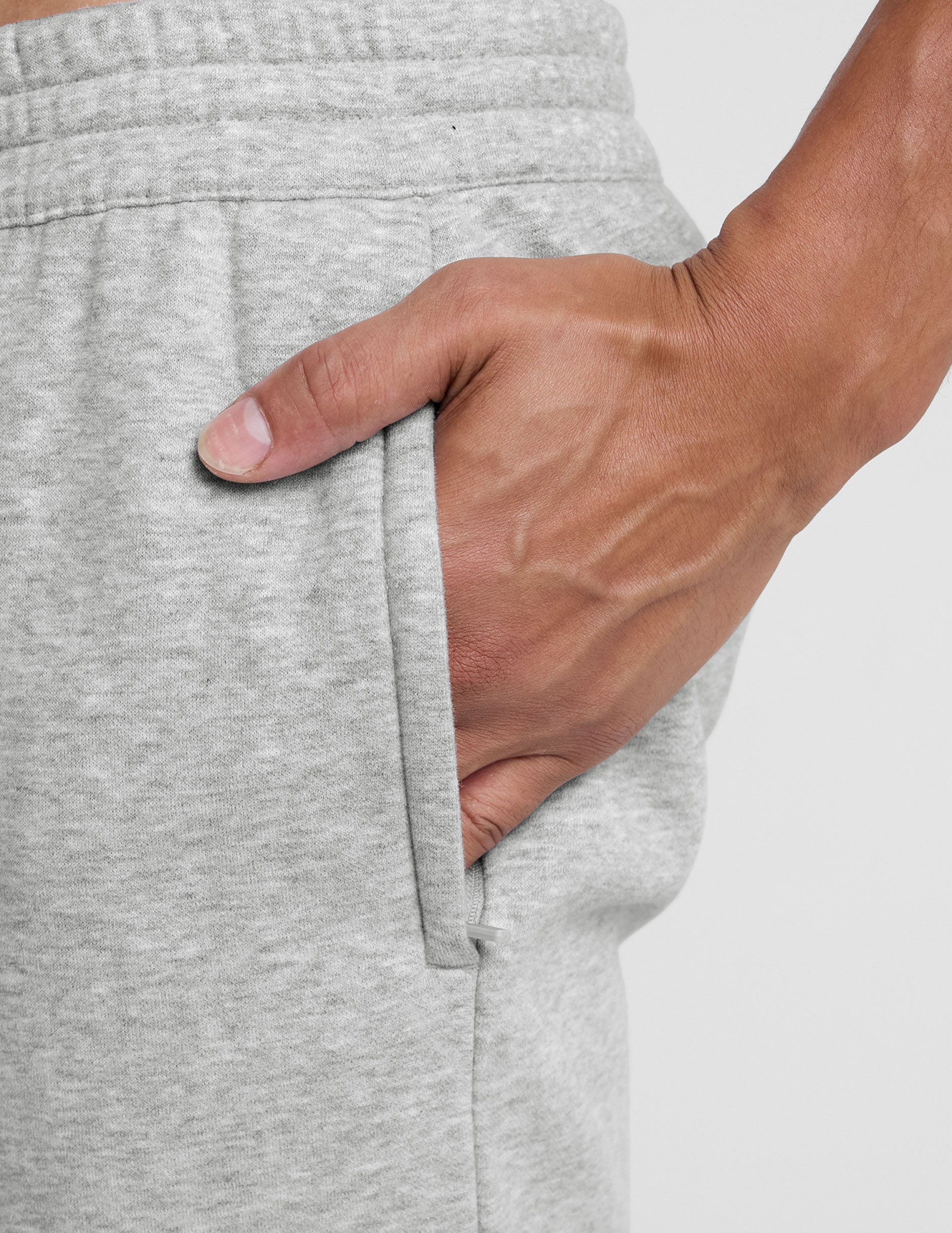 man wearing a gray straight leg fleece sweatpants on a plain background.