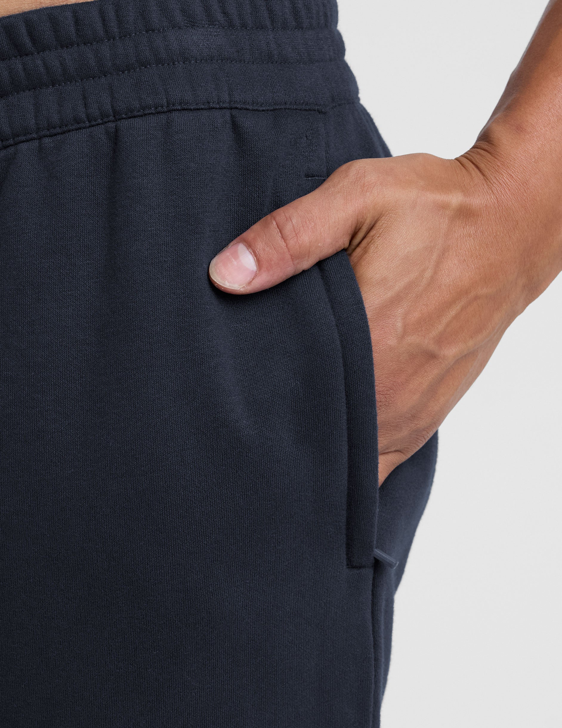 man wearing navy blue straight leg fleece sweatpants on a plain background.