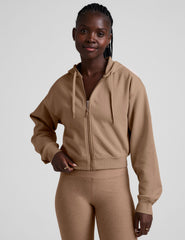 model wearing a brown fleece zip-up hoodie and leggings set on a plain background.