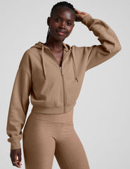 model wearing a brown fleece zip-up hoodie and leggings set on a plain background.