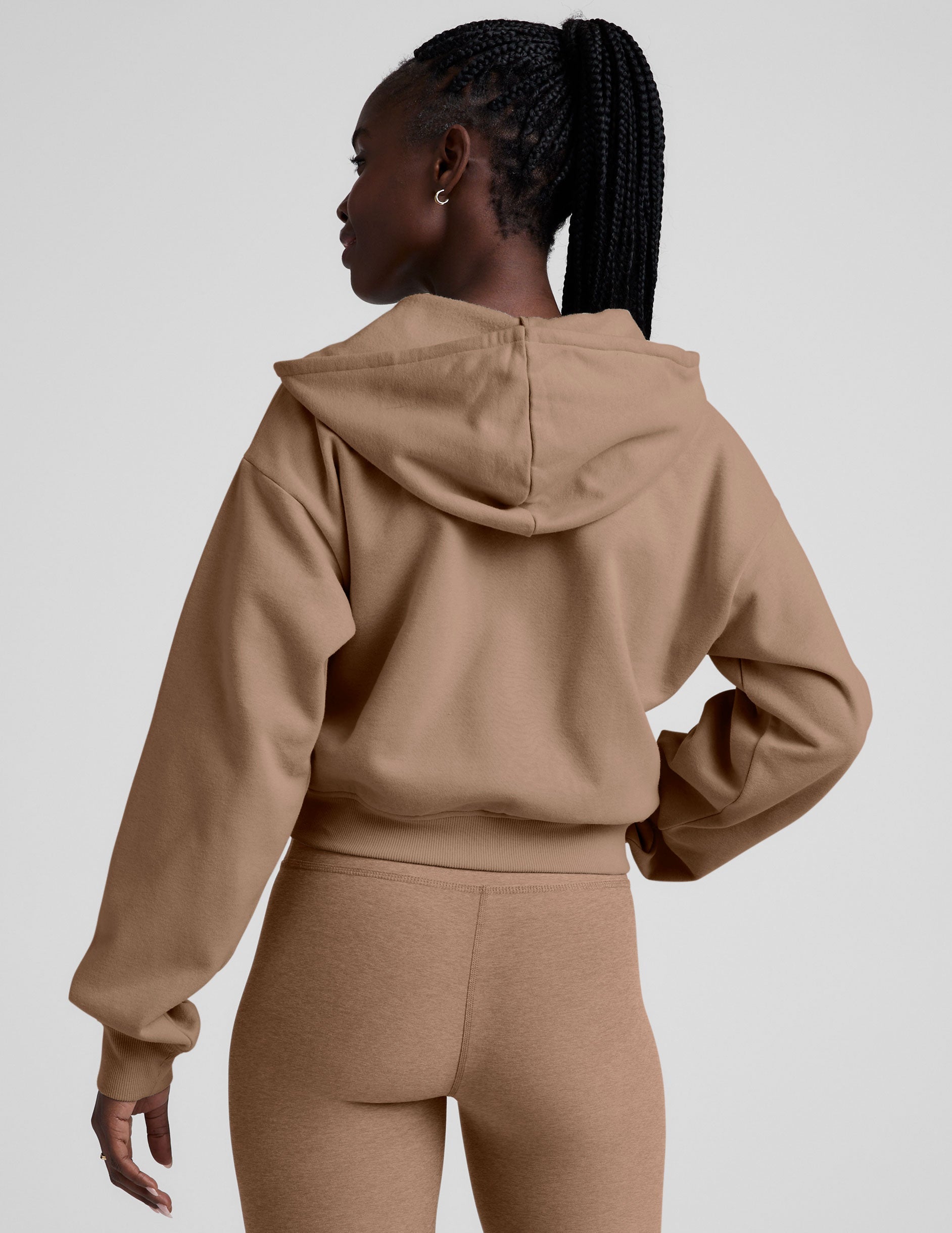 model wearing a brown fleece zip-up hoodie and leggings set on a plain background.