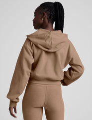 model wearing a brown fleece zip-up hoodie and leggings set on a plain background.