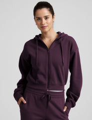 model wearing a purple fleece zip-up hoodie and fleece wide leg pants on a plain background.