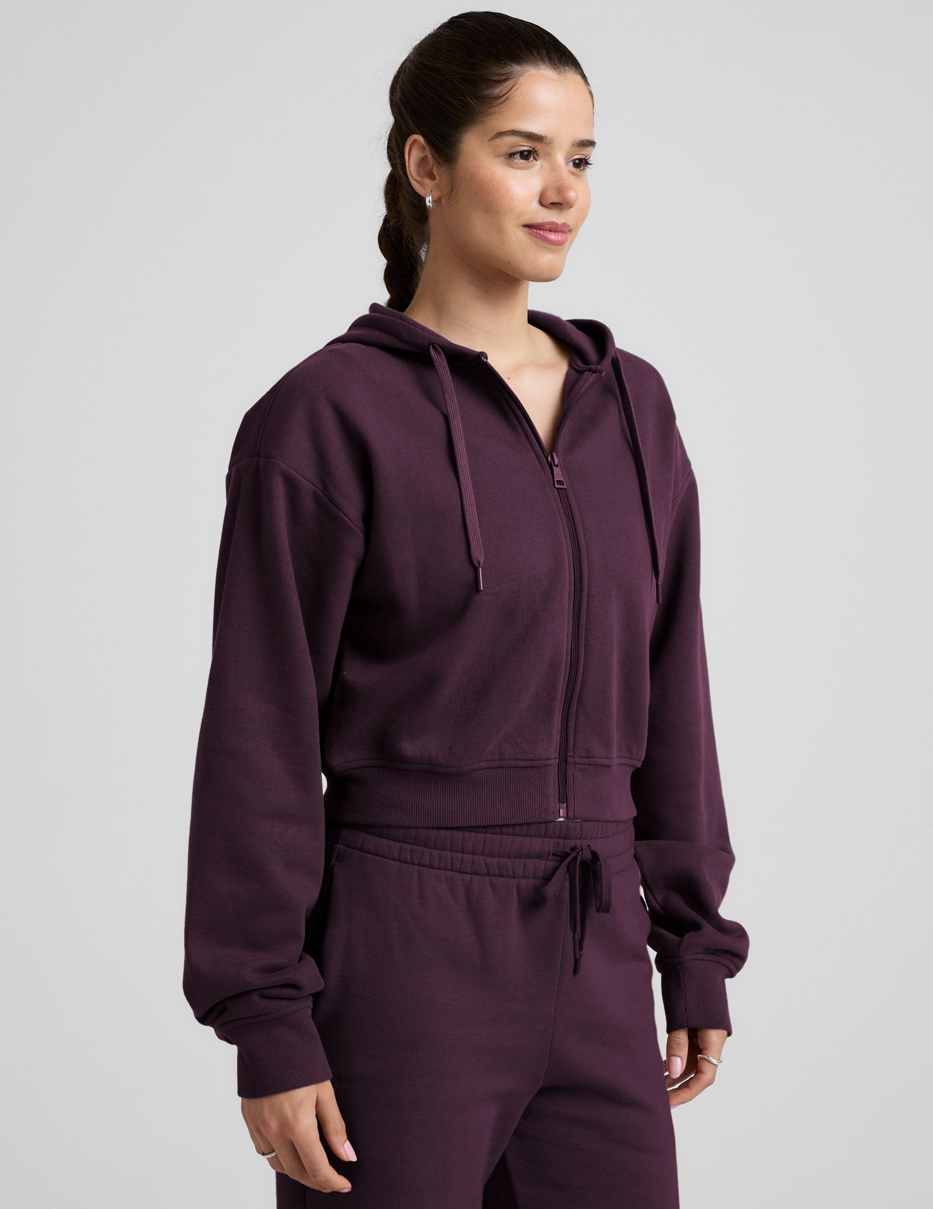 model wearing a purple fleece zip-up hoodie and fleece wide leg pants on a plain background.
