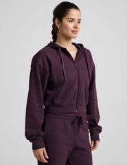model wearing a purple fleece zip-up hoodie and fleece wide leg pants on a plain background.