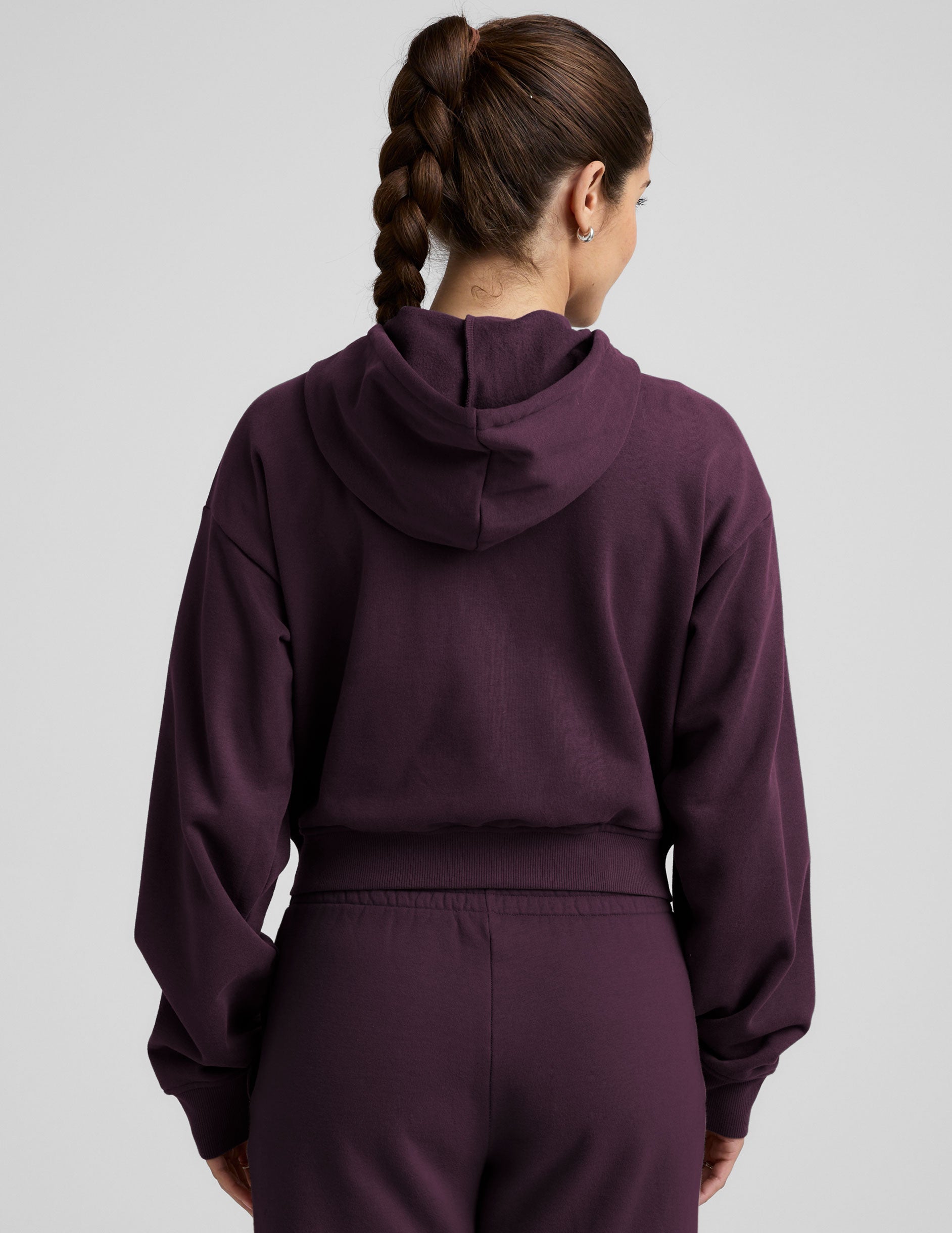 model wearing a purple fleece zip-up hoodie and fleece wide leg pants on a plain background.