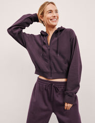 model wearing a purple fleece zip-up hoodie and fleece wide leg pants on a plain background.