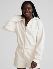 model wearing a white fleece zip-up hoodie and fleece sweat shorts with a drawcord at waistband on a plain background.