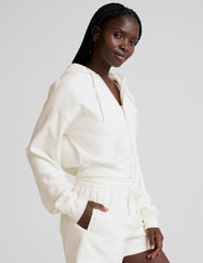 model wearing a white fleece zip-up hoodie and fleece sweat shorts with a drawcord at waistband on a plain background.