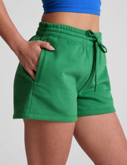 green sweat shorts with pockets and a drawstring at waistband.