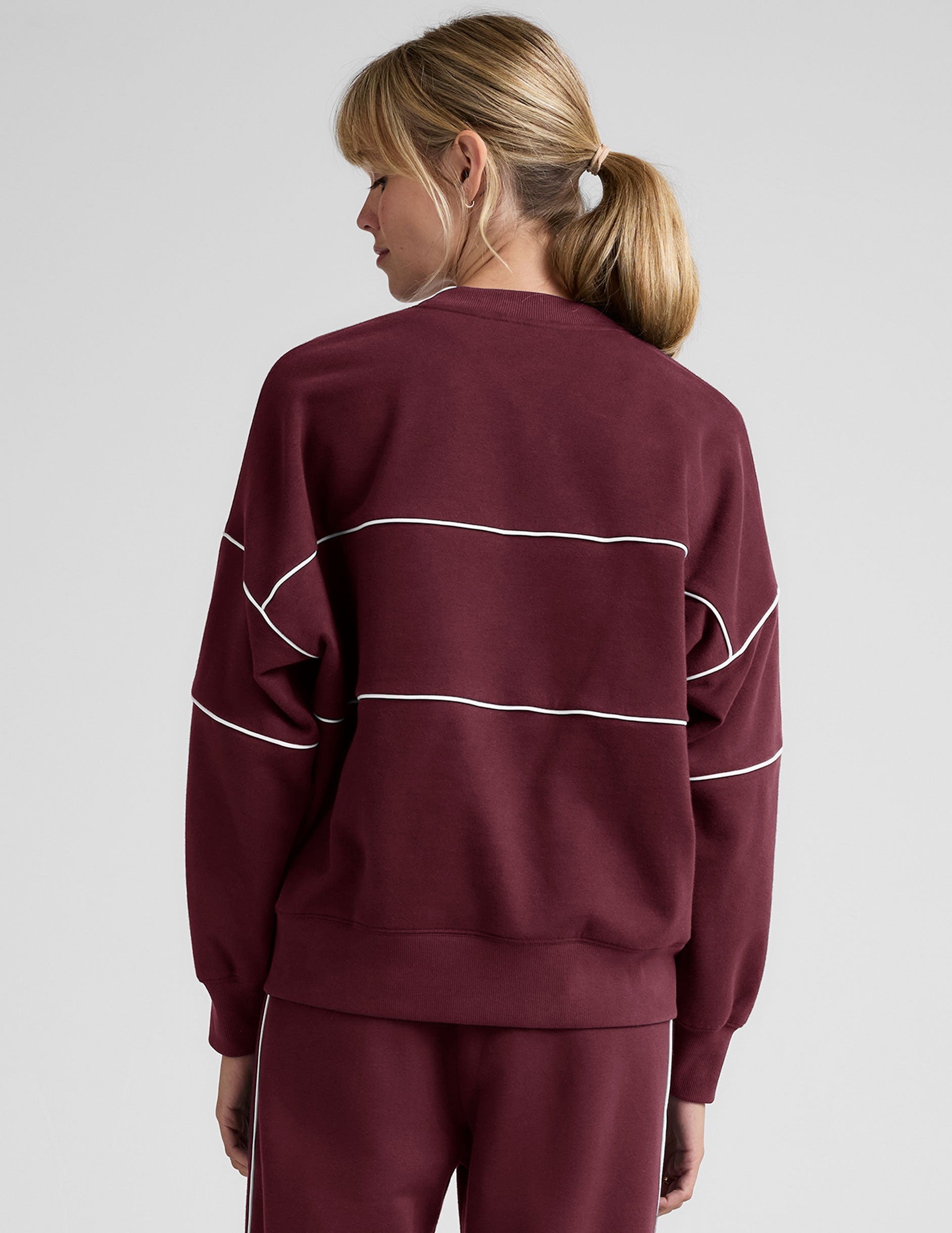 red fleece crewneck sweater with white contrast piping trim at chest and sleeves.