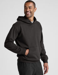 man wearing a black hoodie on a plain background.