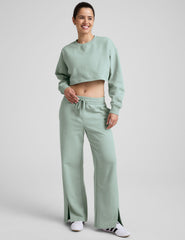 model wearing a light blue boxy fit cropped sweatshirt and fleece pants on a plain background.