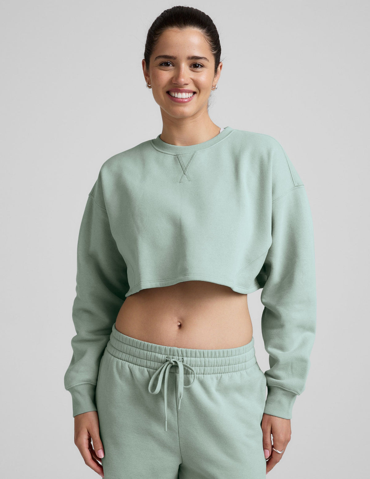 model wearing a light blue boxy fit cropped sweatshirt and fleece pants on a plain background.