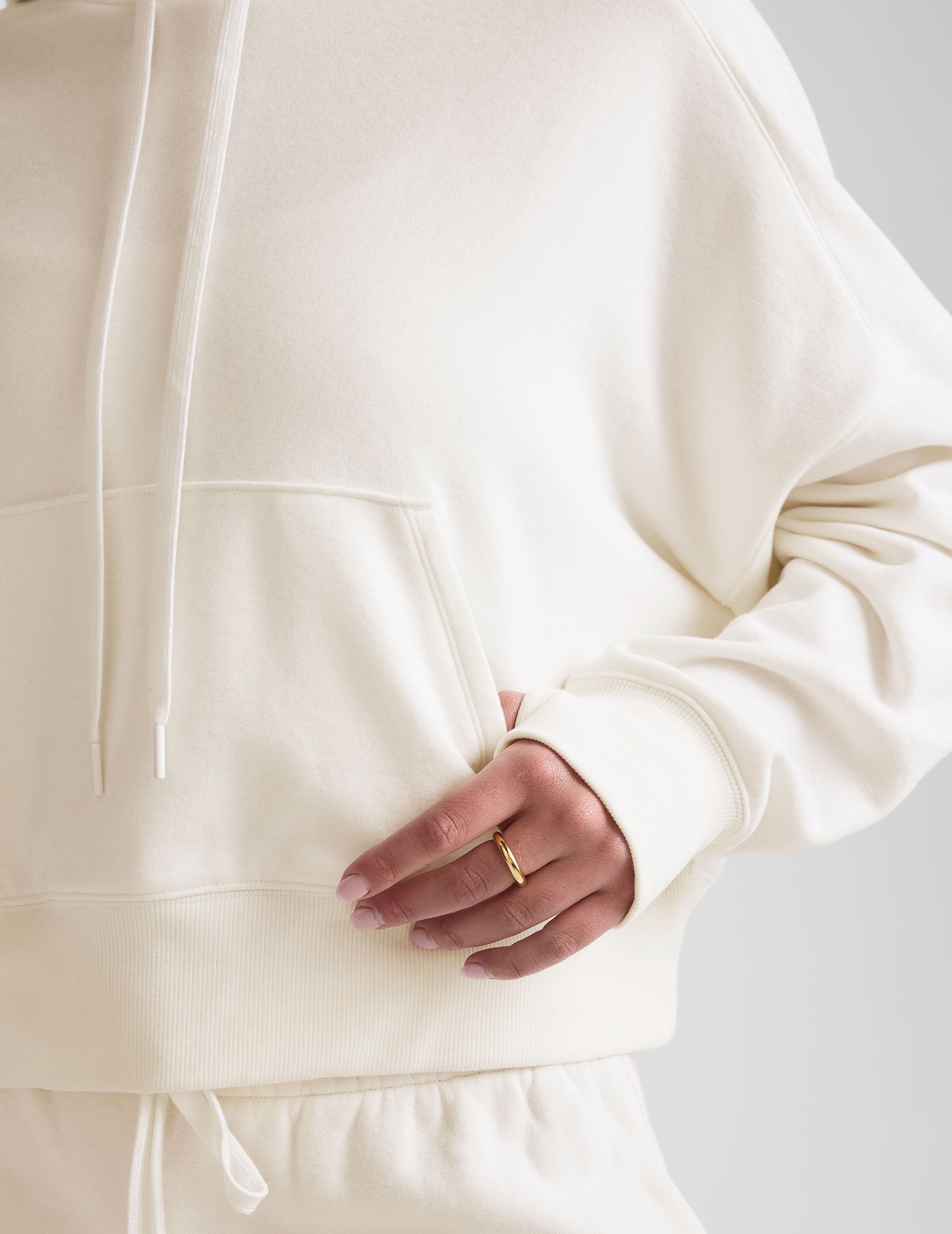 white cropped pullover with a hood with drawcord and a kangaroo pocket.