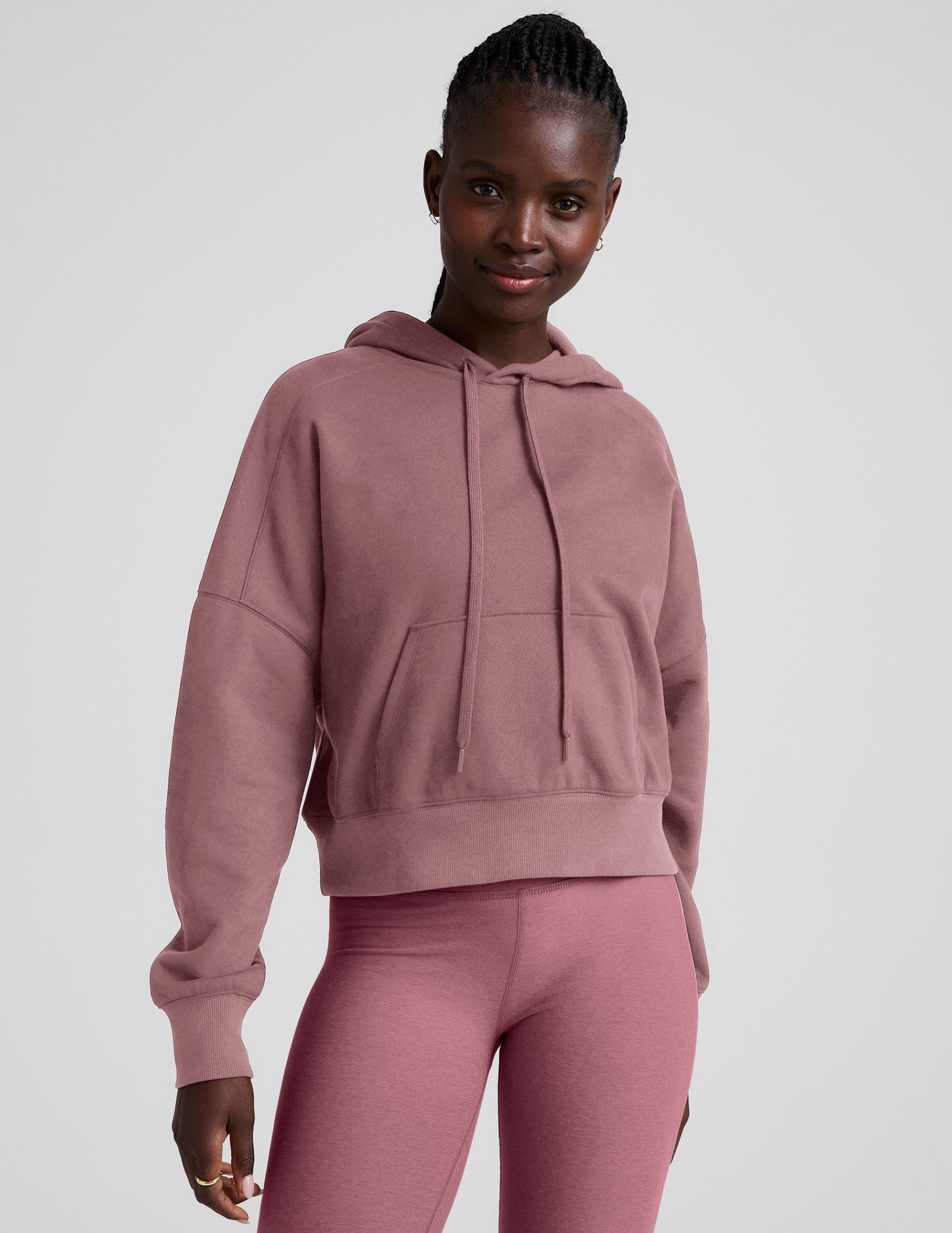pink cropped pullover with a hood with drawcord and a kangaroo pocket.