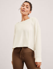 model wearing a cream sweater and brown leggings against a light background.