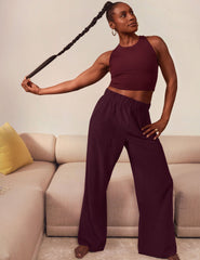 Issa Rae in burgundy top and wide-leg pants posing in a living room.