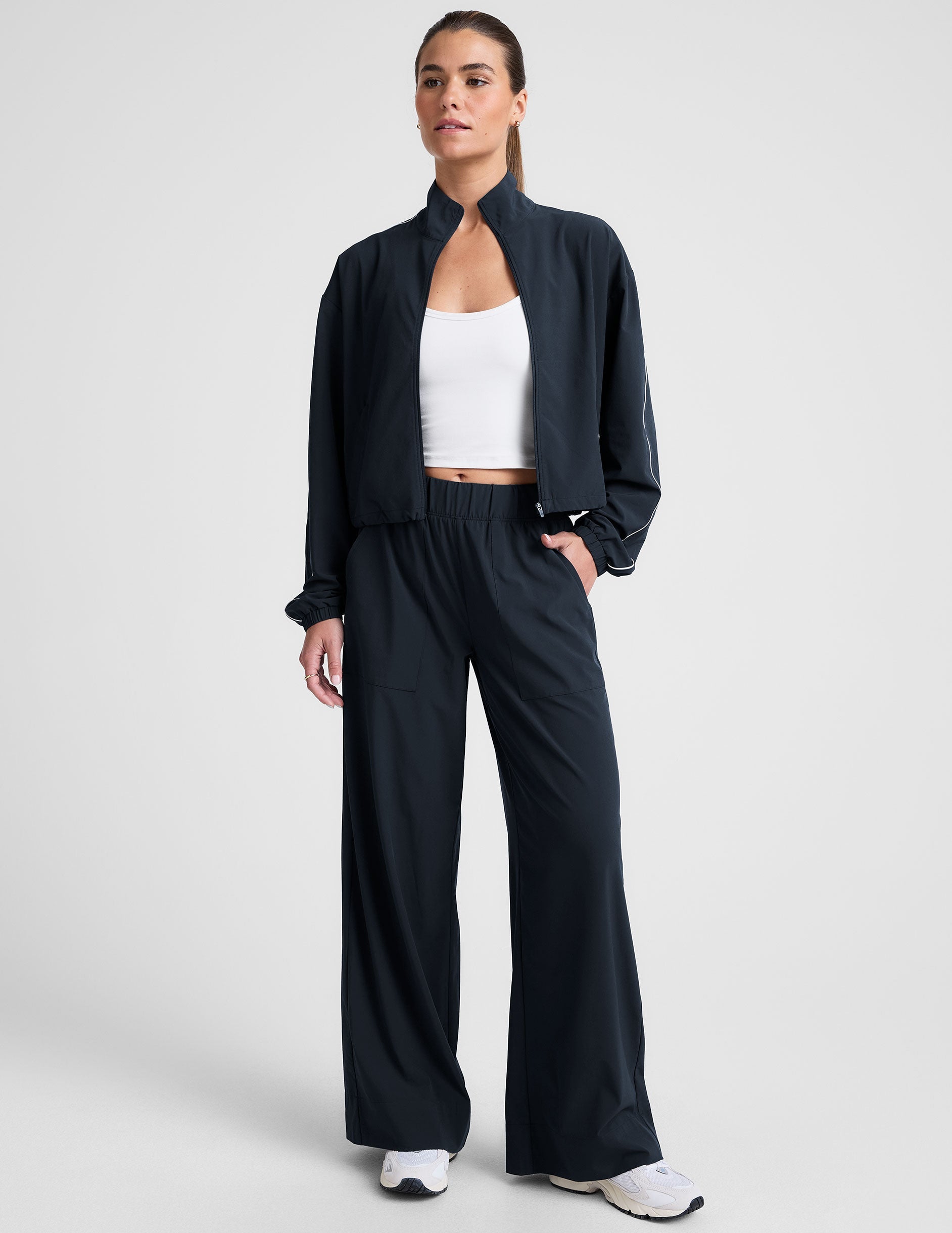 model wearing a blue track jacket with white piping detail on a light gray background.