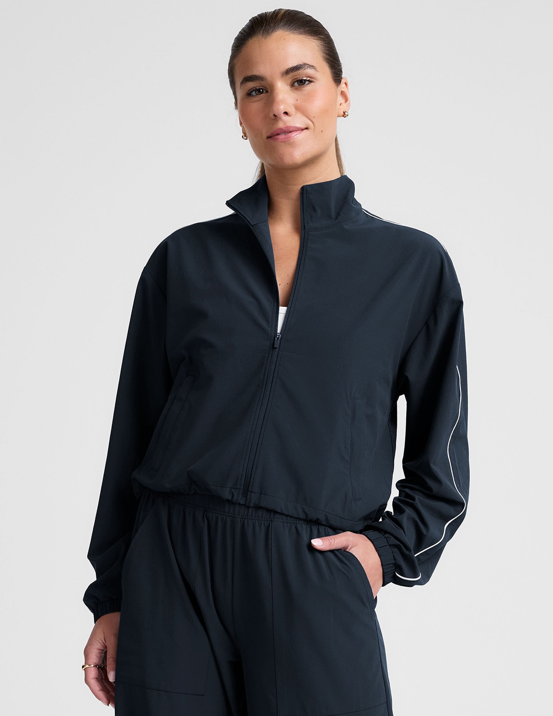 model wearing a blue track jacket with white piping detail on a light gray background.