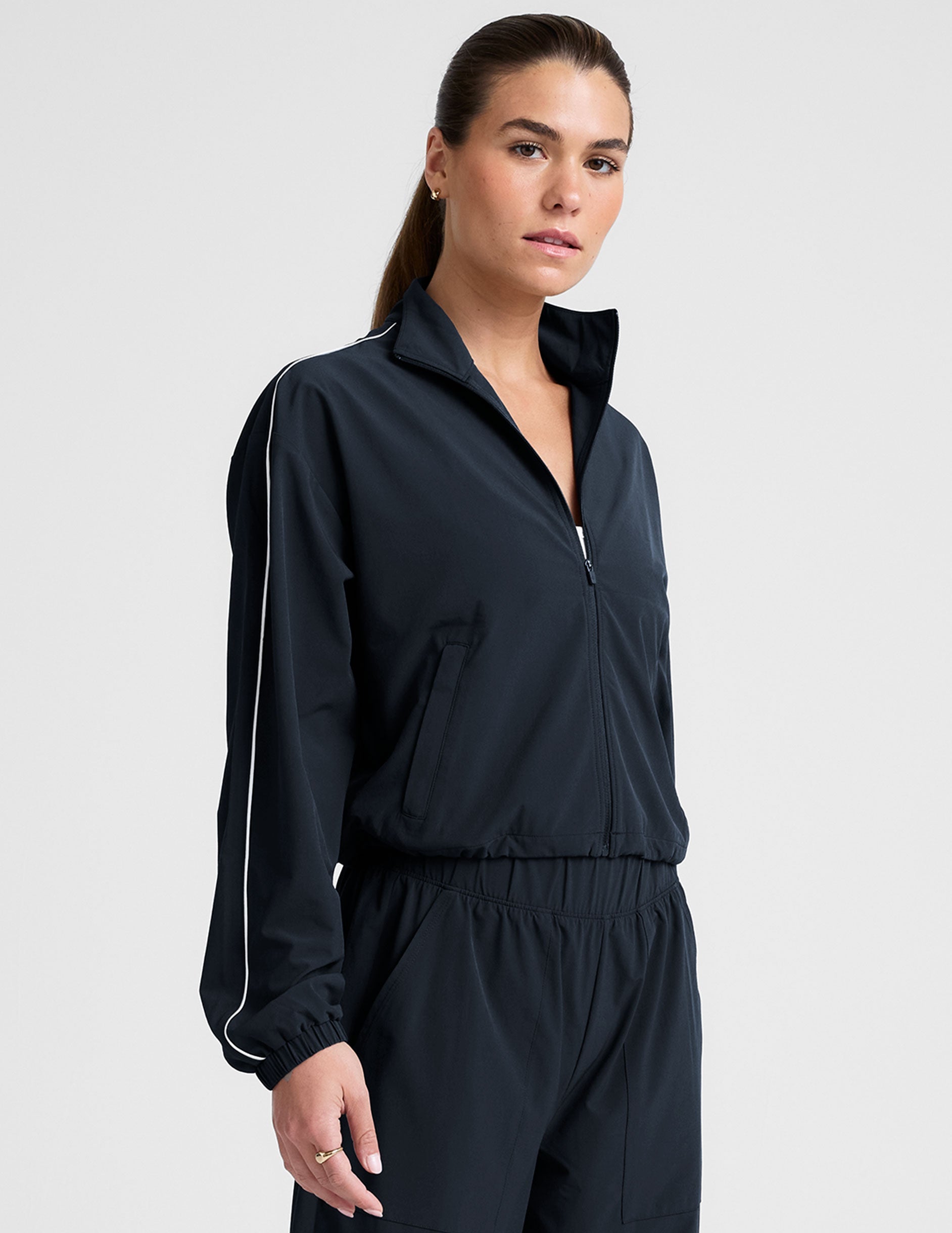 model wearing a blue track jacket with white piping detail on a light gray background.