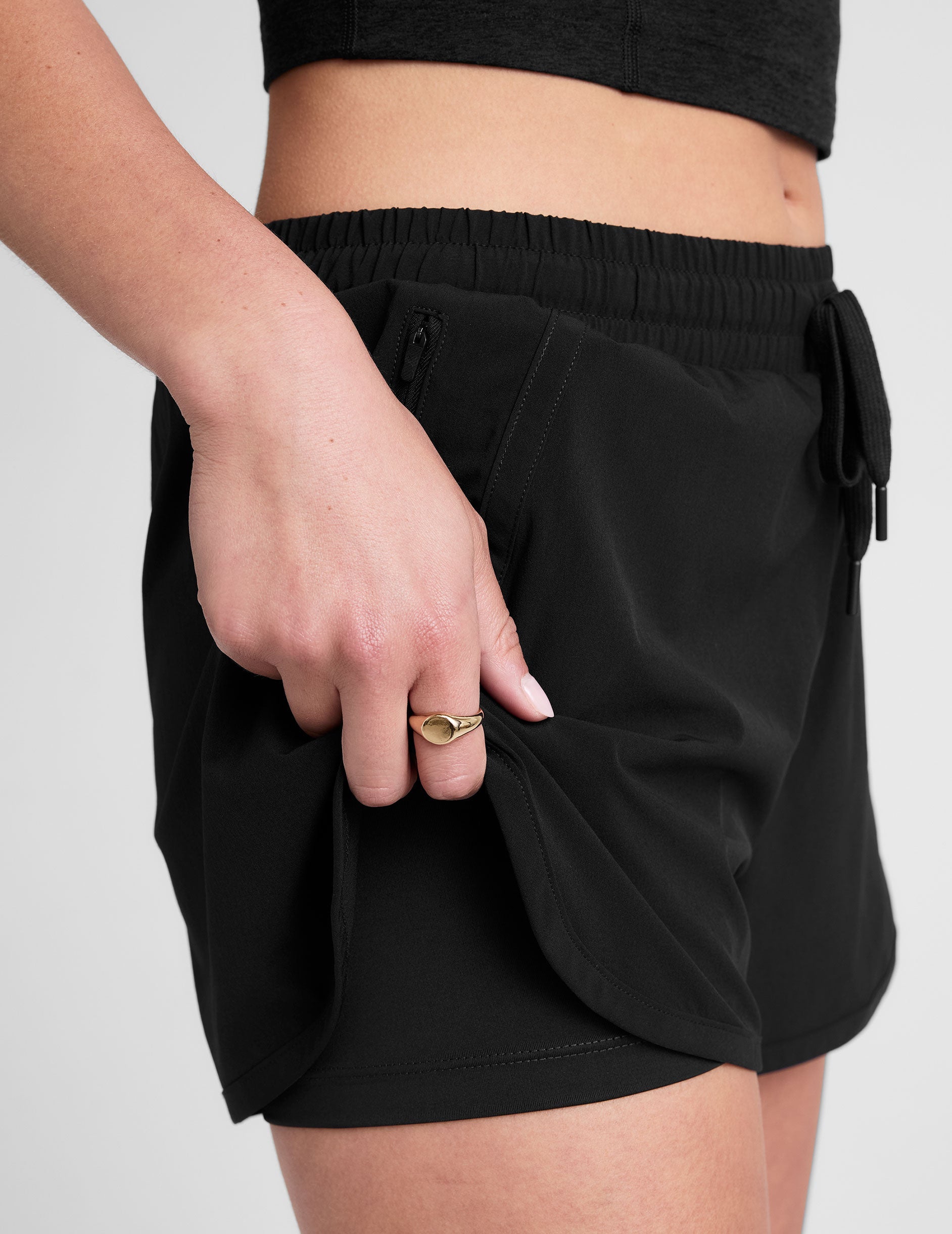 black shorts with a 2.5" inseam, encased elastic at waistband with drawcord​, self binding at hem edges​, side zipper pockets, and interior performance lining shorts​. 