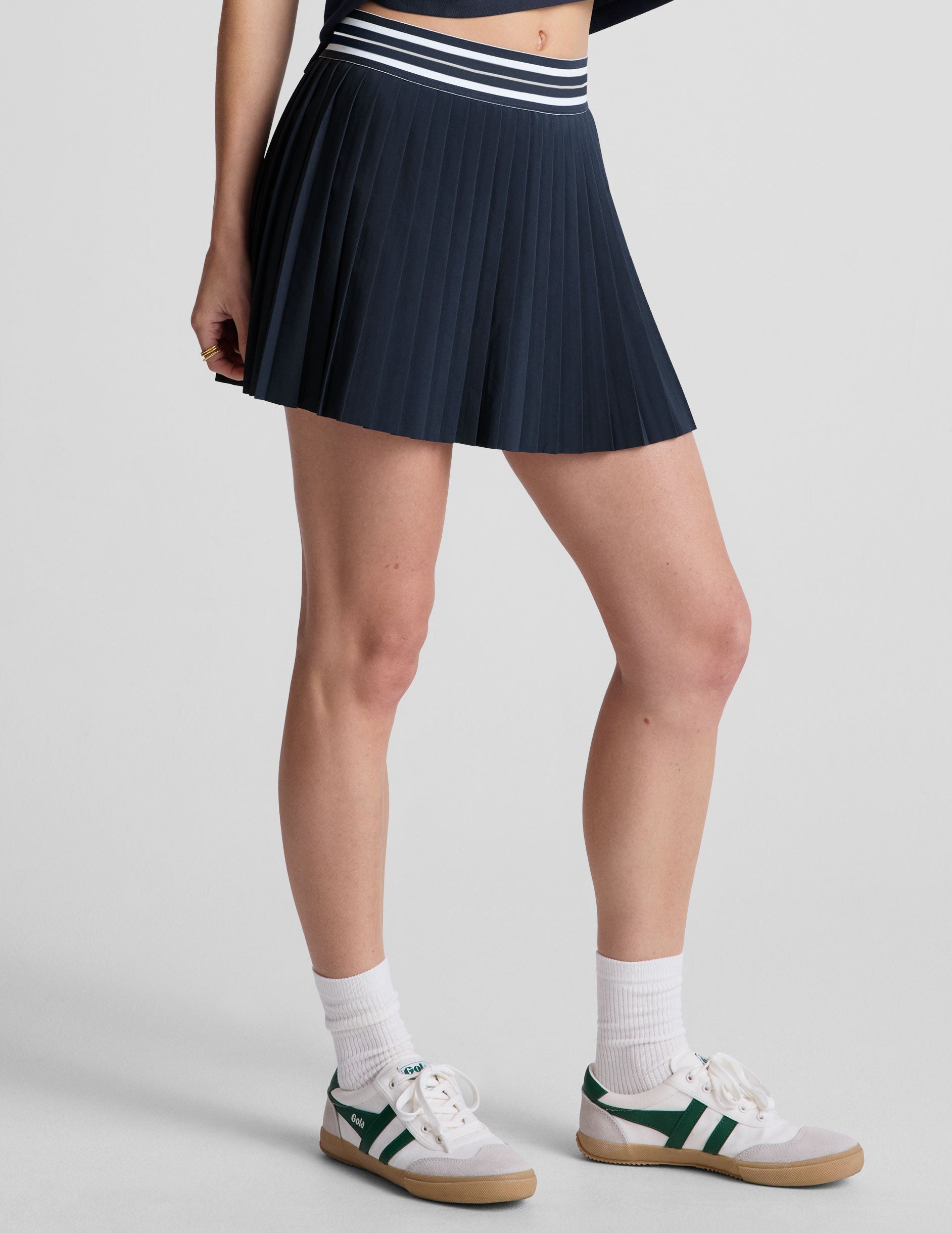 blue mini length pleated skirt with an exposed stripped elastic waistband​ and 
internal performance shorts with pockets​. 