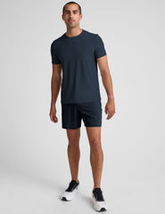 man wearing a navy t-shirt and blue shorts on a white background.