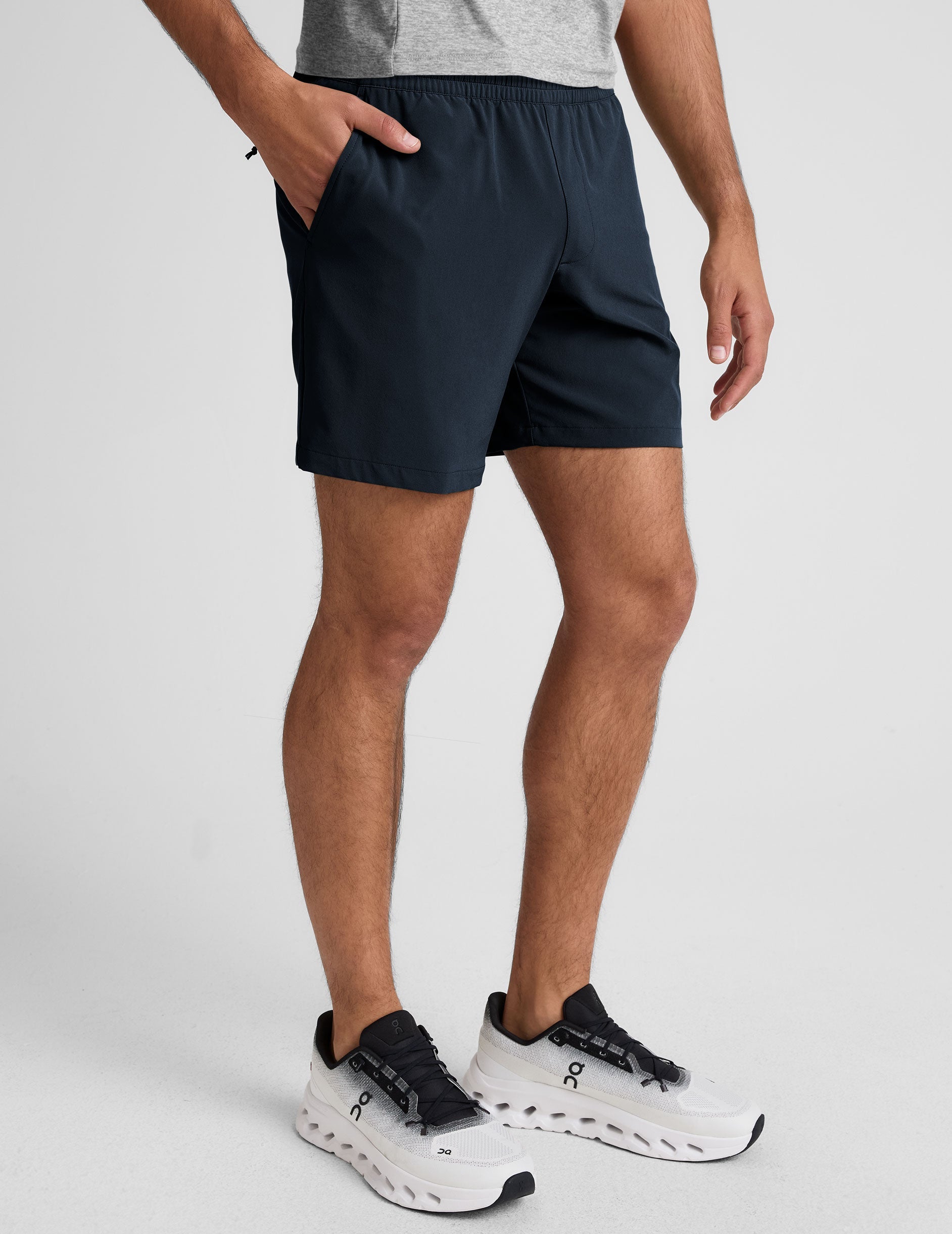 man wearing a navy t-shirt and blue shorts on a white background.