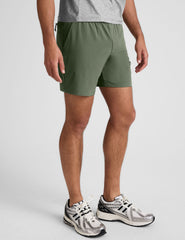 man wearing a gray t-shirt and green shorts on a white background.